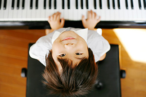 Boy playing piano, looking up at the camera
